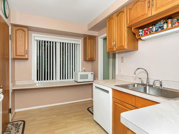 23165 Church St, Oak Park, MI 48237 - kitchen featuring white appliances, a sink, light wood-style flooring, and light countertops