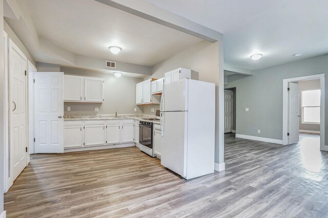 407 11th St NW Unit 409, Grand Rapids, MI 49504 - kitchen with freestanding refrigerator, range with gas stovetop, light wood-type flooring, white cabinetry, and a sink