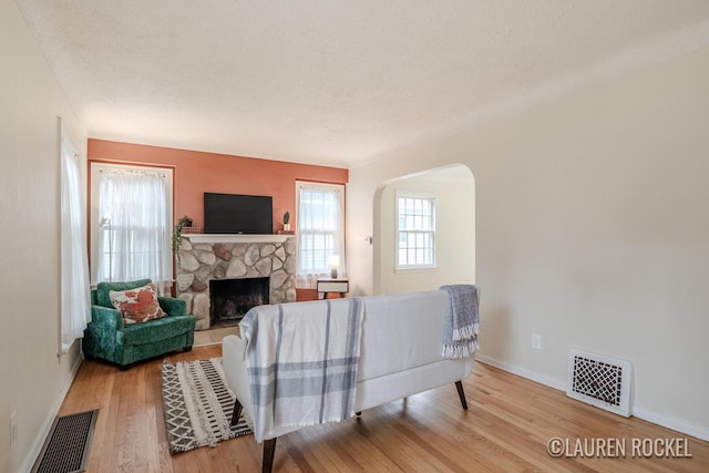 839 Joslin St SE, Grand Rapids, MI 49507 - living room featuring a fireplace, wood finished floors, baseboards, arched walkways, and a textured ceiling