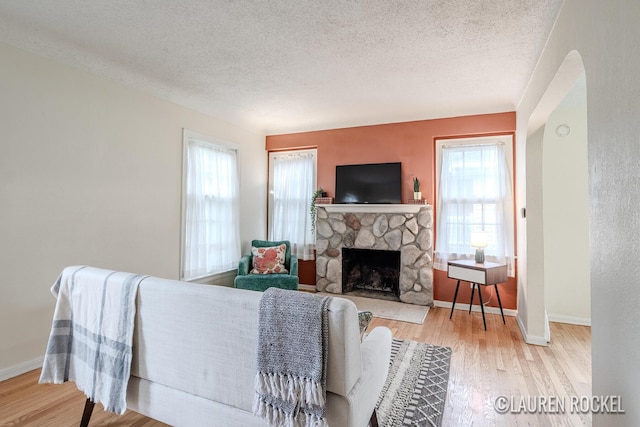 839 Joslin St SE, Grand Rapids, MI 49507 - living room with healthy amount of natural light, a fireplace, wood finished floors, a textured ceiling, and baseboards