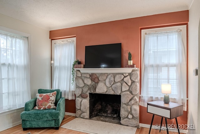 839 Joslin St SE, Grand Rapids, MI 49507 - living area featuring wood finished floors, a fireplace, baseboards, and a textured ceiling