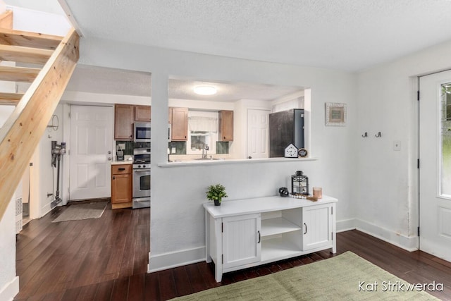 1900 Kinney Ave NW, Grand Rapids, MI 49534 - kitchen featuring appliances with stainless steel finishes, dark wood-style floors, light countertops, a sink, and a textured ceiling