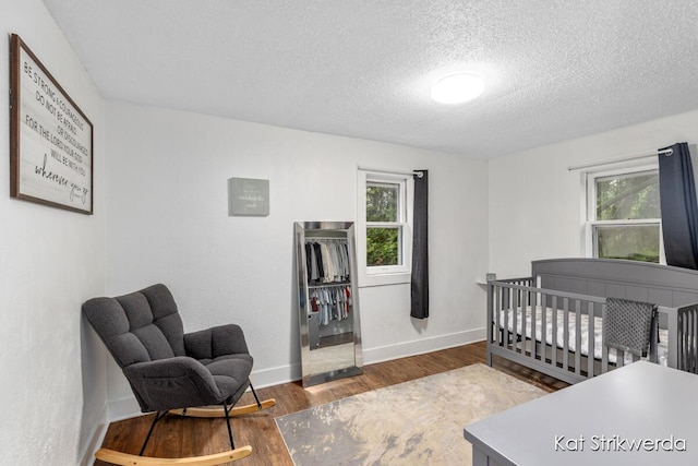 1900 Kinney Ave NW, Grand Rapids, MI 49534 - bedroom with wood finished floors, multiple windows, a textured ceiling, and baseboards