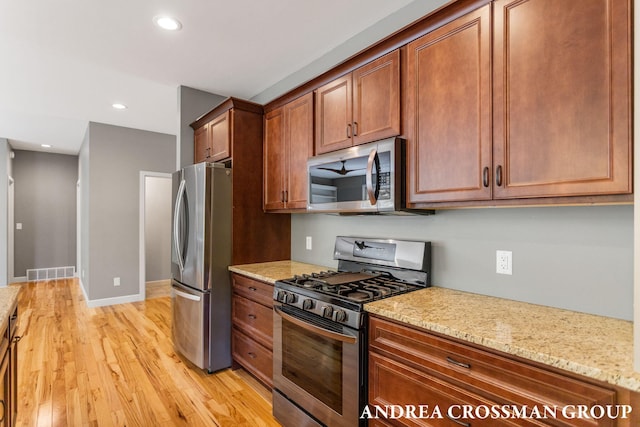 17946 Robbins Rd, Grand Haven, MI 49417 - kitchen with stainless steel appliances, light wood-style flooring, light stone countertops, brown cabinets, and recessed lighting
