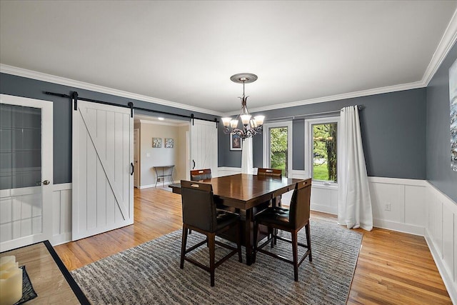 4047 Ramsgate Ct, Ann Arbor, MI 48103 - dining area featuring a barn door, light wood-style floors, ornamental molding, a chandelier, and wainscoting