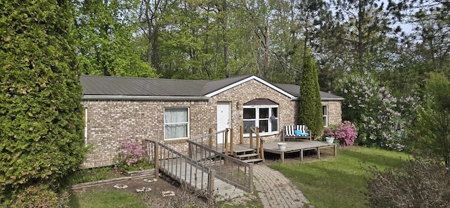 1200 E Ave, Harrison, MI 48625 - rear view of house featuring brick siding, a wooden deck, metal roof, and a yard