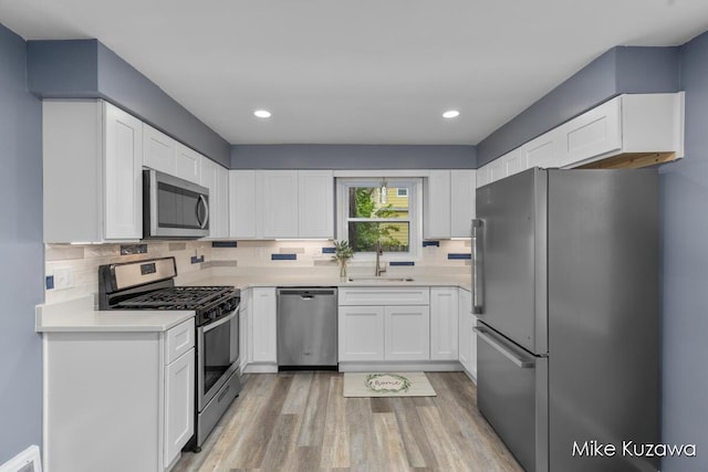 945 NW Dorothy St NW, Grand Rapids, MI 49504 - kitchen with appliances with stainless steel finishes, a sink, light wood-type flooring, white cabinets, and recessed lighting
