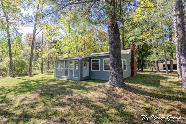 1261 W Channel St, Bitely, MI 49309 - view of front of home with a chimney, a sunroom, and a front yard