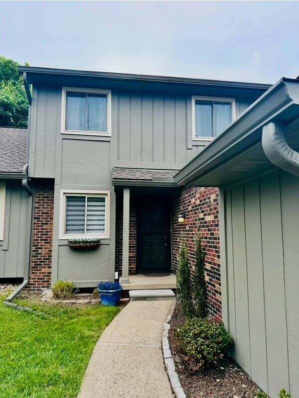 44750 Erin Dr, Plymouth, MI 48170 - property entrance featuring board and batten siding, brick siding, and roof with shingles