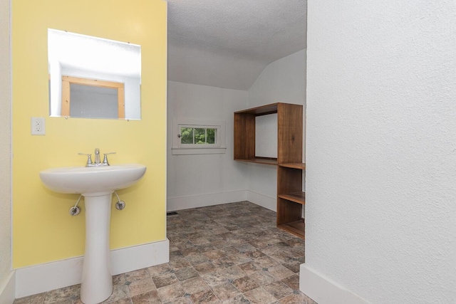 7610 W Kl Ave, Kalamazoo, MI 49009 - bathroom with baseboards, stone finish floors, lofted ceiling, a textured ceiling, and a sink