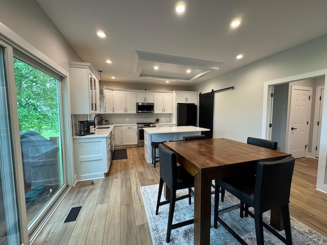 8460 Woodridge Dr, Davison, MI 48423 - dining space with a barn door, a raised ceiling, light wood finished floors, and recessed lighting