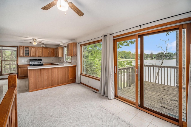 13085 S Englewright Dr, Sand Lake, MI 49343 - kitchen with range with gas stovetop, a ceiling fan, brown cabinetry, a sink, and healthy amount of natural light