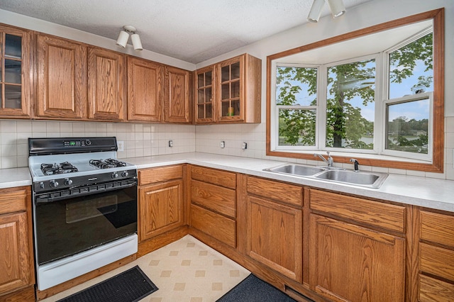13085 S Englewright Dr, Sand Lake, MI 49343 - kitchen featuring gas range, a sink, brown cabinets, backsplash, and light countertops