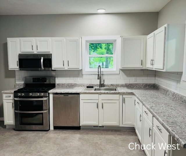 1479 Terrace St, Muskegon, MI 49442 - kitchen featuring stainless steel appliances, a sink, backsplash, white cabinetry, and light countertops
