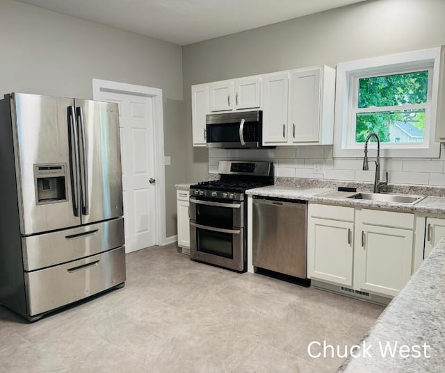 1479 Terrace St, Muskegon, MI 49442 - kitchen with stainless steel appliances, a sink, white cabinetry, and backsplash