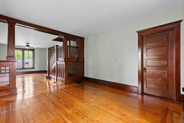 8001 S Jackson Rd, Jackson, MI 49201 - spare room with light wood finished floors, baseboards, ornate columns, stairs, and a ceiling fan