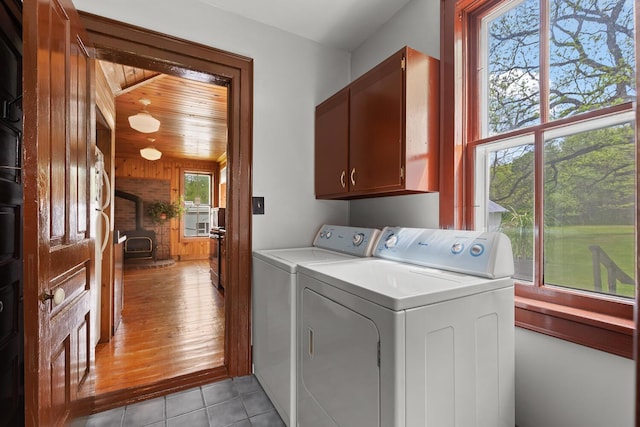 8001 S Jackson Rd, Jackson, MI 49201 - laundry area featuring cabinet space, a wood stove, separate washer and dryer, wooden walls, and light tile patterned floors