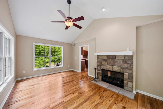64711 Shorewood Ln, Cassopolis, MI 49031 - unfurnished living room featuring vaulted ceiling, light wood-style flooring, a stone fireplace, a ceiling fan, and baseboards