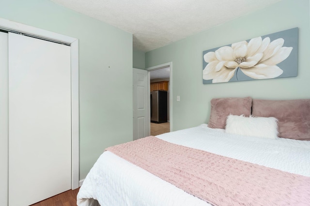 4121 Quebec St, Auburn Hills, MI 48326 - bedroom featuring freestanding refrigerator, a closet, wood finished floors, and a textured ceiling