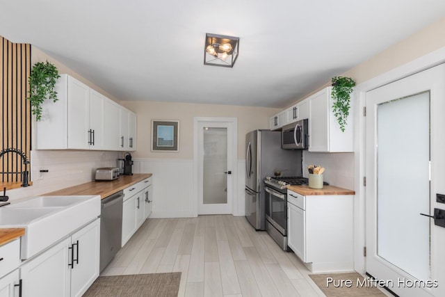 912 Arianna St NW, Grand Rapids, MI 49504 - kitchen featuring stainless steel appliances, wooden counters, a sink, light wood-style floors, and white cabinets