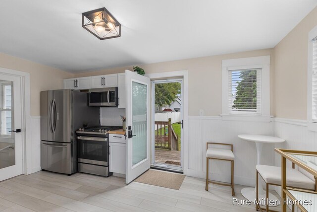 912 Arianna St NW, Grand Rapids, MI 49504 - kitchen with appliances with stainless steel finishes, wainscoting, light wood-style floors, and light countertops
