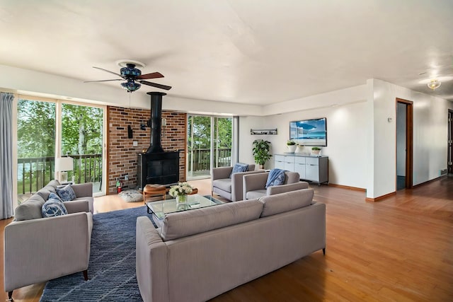 4771 S Lakeshore Dr, Ludington, MI 49431 - living area featuring a wood stove, a ceiling fan, wood finished floors, and baseboards