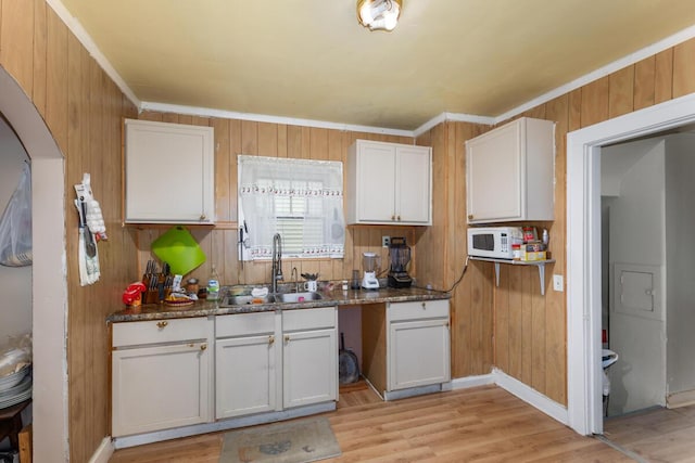 2113 Palace Ave SW, Grand Rapids, MI 49507 - kitchen featuring a sink, white cabinetry, light wood finished floors, wooden walls, and crown molding