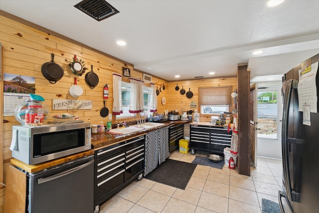 806 W Centre Ave, Portage, MI 49024 - kitchen featuring stainless steel microwave, wood walls, freestanding refrigerator, light tile patterned flooring, and recessed lighting