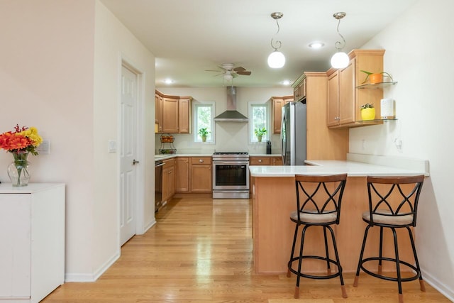 2501 Holiday House Rd, Saint Joseph, MI 49085 - kitchen featuring stainless steel appliances, wall chimney exhaust hood, a peninsula, light wood finished floors, and a breakfast bar