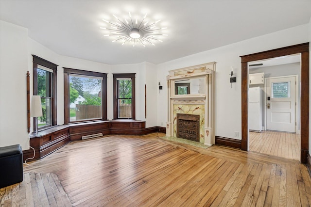 904 Schuring Rd, Portage, MI 49024 - unfurnished living room with light wood finished floors, a premium fireplace, a chandelier, and baseboards
