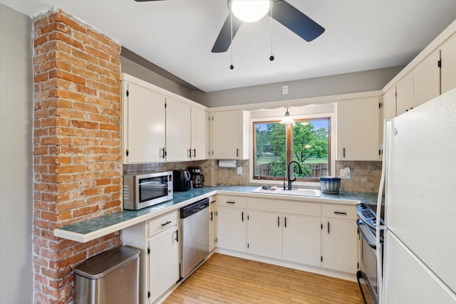 904 Schuring Rd, Portage, MI 49024 - kitchen featuring appliances with stainless steel finishes, a sink, decorative backsplash, light wood-style flooring, and a ceiling fan