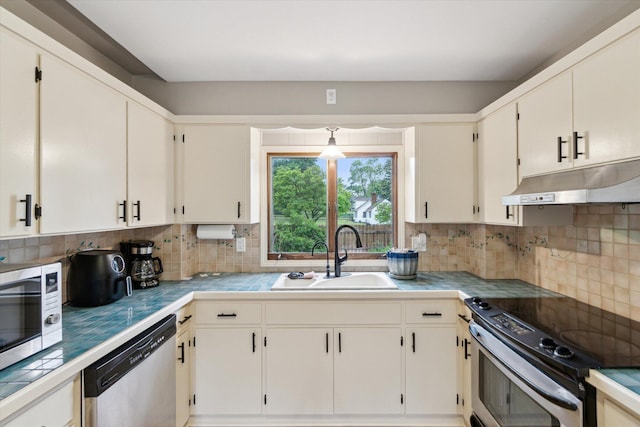 904 Schuring Rd, Portage, MI 49024 - kitchen featuring appliances with stainless steel finishes, a sink, under cabinet range hood, and decorative backsplash