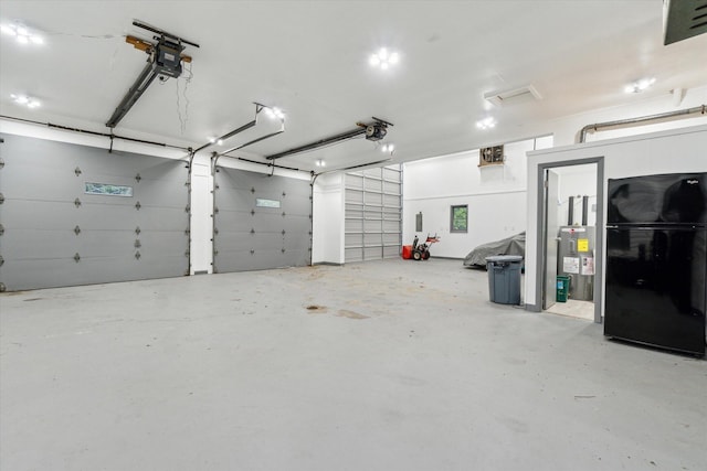 904 Schuring Rd, Portage, MI 49024 - garage featuring freestanding refrigerator, water heater, and a garage door opener