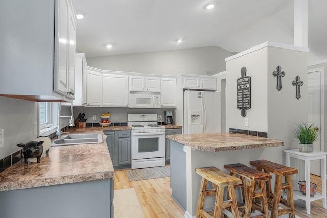 121 W Calgary Dr, Hastings, MI 49058 - kitchen featuring white appliances, a sink, lofted ceiling, light wood-style flooring, and a breakfast bar area
