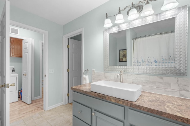 121 W Calgary Dr, Hastings, MI 49058 - full bath featuring vanity, washer / dryer, decorative backsplash, and baseboards