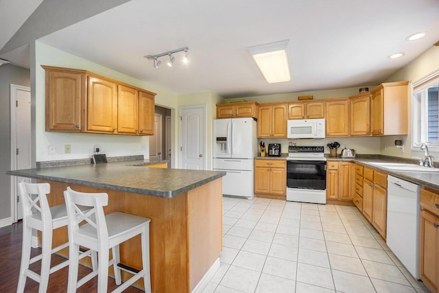 1001 Goodsell St, Otsego, MI 49078 - kitchen featuring white appliances, a sink, dark countertops, a peninsula, and a breakfast bar