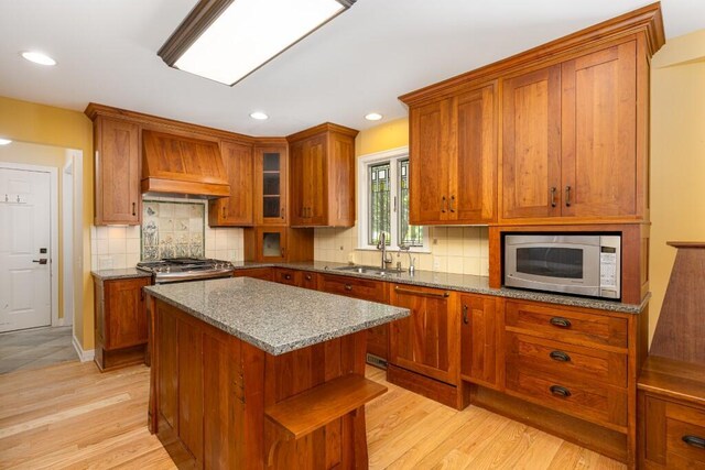 4936 Ravine Ct, Ann Arbor, MI 48105 - kitchen with stainless steel microwave, premium range hood, brown cabinetry, a sink, and recessed lighting