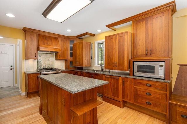 4936 Ravine Ct, Ann Arbor, MI 48105 - kitchen with premium range hood, brown cabinetry, stone counters, light wood-style flooring, and recessed lighting