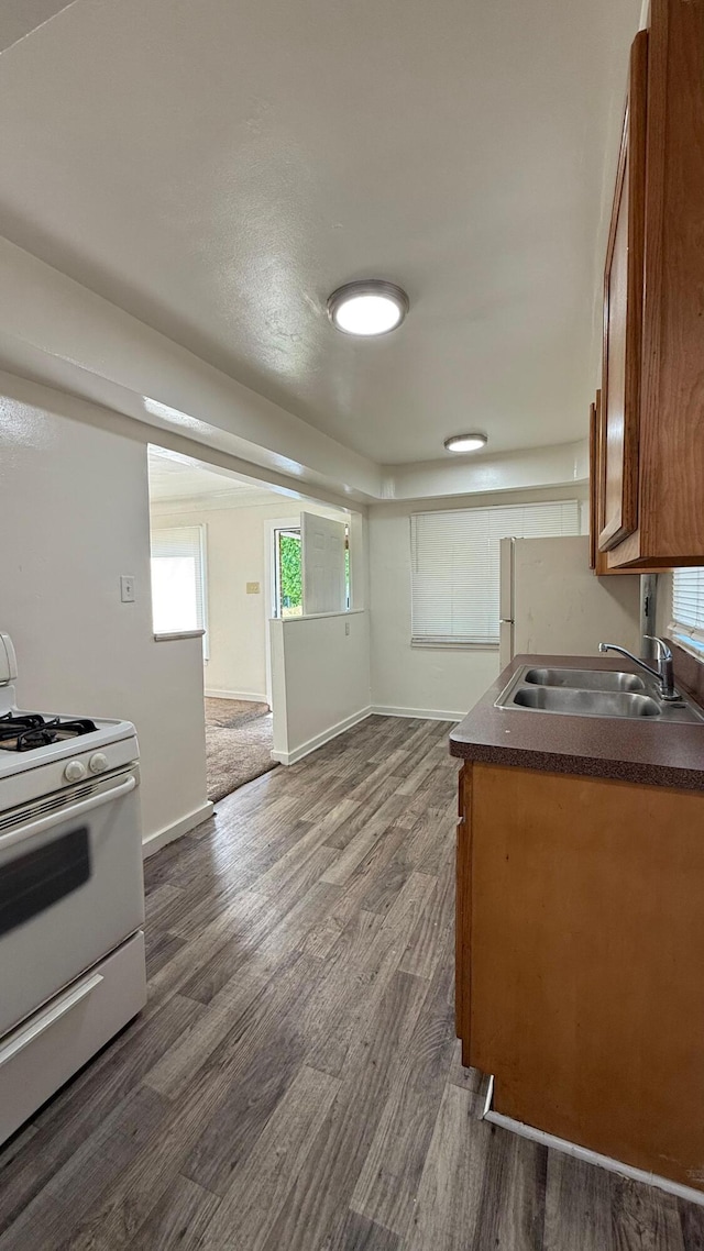 15852 Wabash St, Detroit, MI 48238 - kitchen featuring white range with gas cooktop, a sink, brown cabinets, dark wood finished floors, and dark countertops