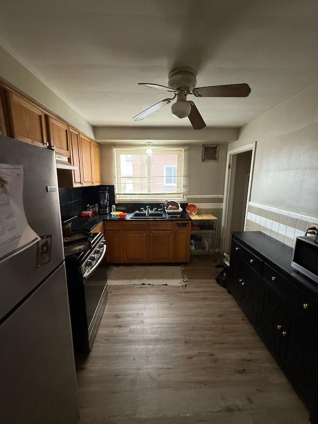16510 Oakfield Ave, Detroit, MI 48235 - kitchen featuring appliances with stainless steel finishes, dark countertops, ceiling fan, under cabinet range hood, and a wainscoted wall