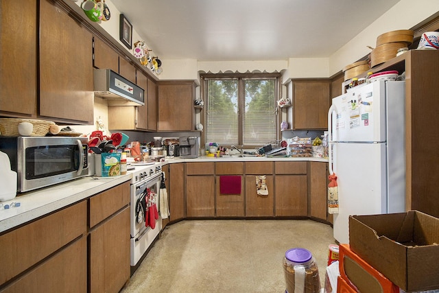 244 W Franklin St, Otsego, MI 49078 - kitchen with white appliances, under cabinet range hood, light countertops, brown cabinetry, and a sink