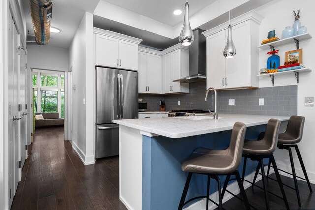 211 W Kingsley St, Ann Arbor, MI 48103 - kitchen with freestanding refrigerator, a peninsula, baseboards, wall chimney range hood, and light stone countertops