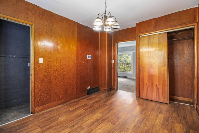 527 Jackson St W, Battle Creek, MI 49037 - unfurnished bedroom featuring a chandelier, wood finished floors, and a closet