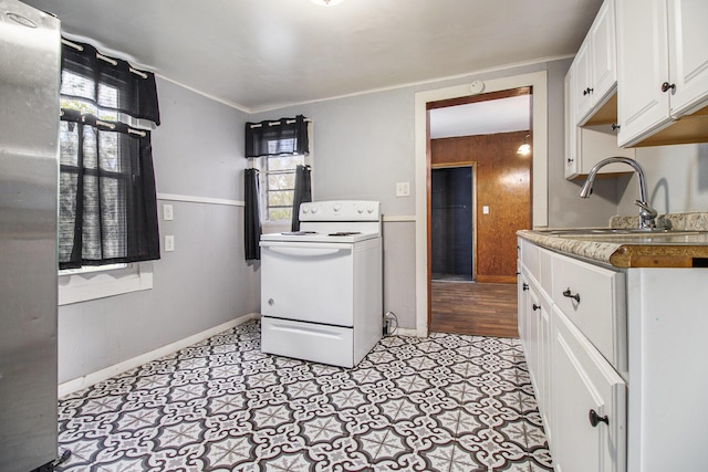 527 Jackson St W, Battle Creek, MI 49037 - kitchen with electric range, a sink, white cabinetry, and baseboards