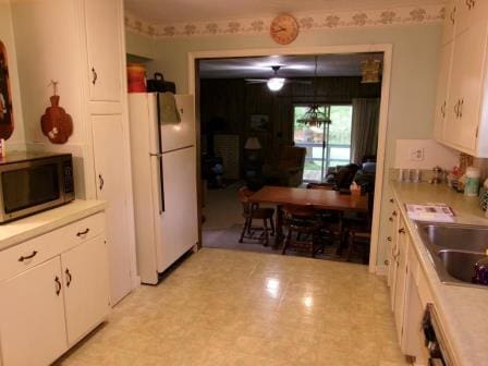 98 Reading Ave, Hillsdale, MI 49242 - kitchen with freestanding refrigerator, stainless steel microwave, white cabinets, and a sink