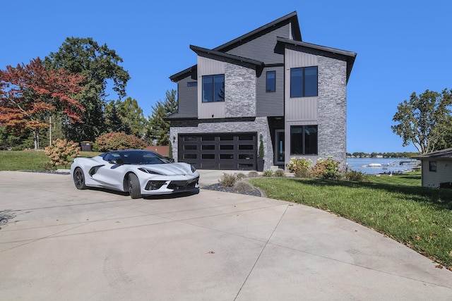 104 Highview Ct, Brooklyn, MI 49230 - contemporary home with driveway, a front lawn, an attached garage, and a water view