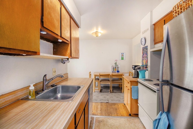 3146 Wolverine Dr, Ann Arbor, MI 48108 - kitchen featuring freestanding refrigerator, white range with electric stovetop, a sink, light countertops, and brown cabinets