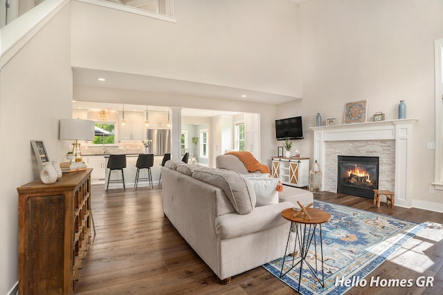 535 N Creek Ct NE, Rockford, MI 49341 - living room with plenty of natural light, dark wood-style floors, a stone fireplace, a towering ceiling, and recessed lighting