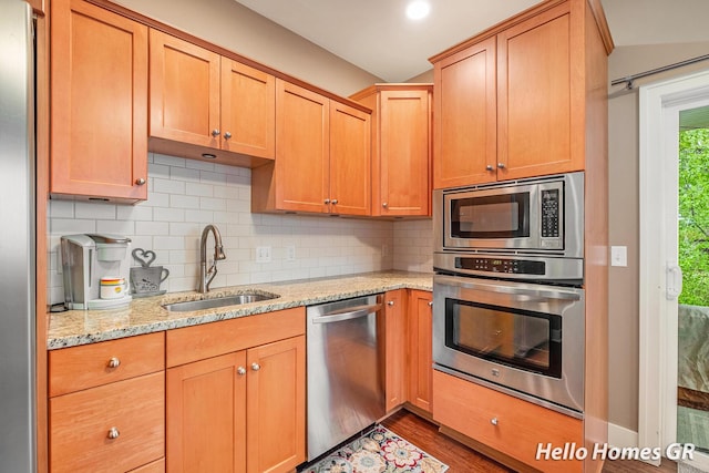535 N Creek Ct NE, Rockford, MI 49341 - kitchen with stainless steel appliances, a sink, wood finished floors, decorative backsplash, and light stone countertops