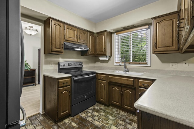 14436 Fairway St, Livonia, MI 48154 - kitchen with black range with electric stovetop, under cabinet range hood, a sink, freestanding refrigerator, and brick patterned flooring